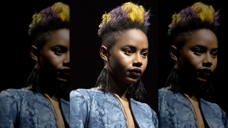 Une personne avec un pompadour coloré et des boucles d'oreilles franges