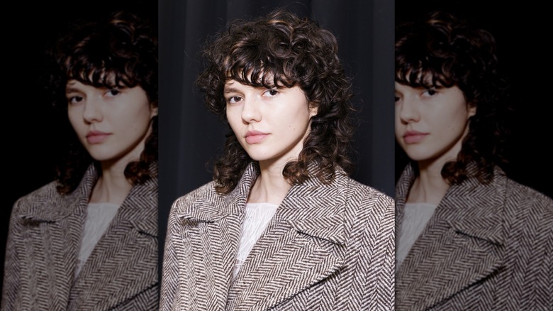 Une personne avec une coupe de loup bouclé portant un blazer