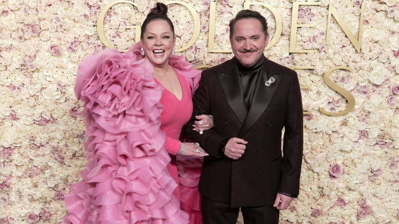 Melissa McCarthy et Ben Falcone foulent le tapis des Golden Globes 2025 dans une robe rose et un costume noir, respectivement