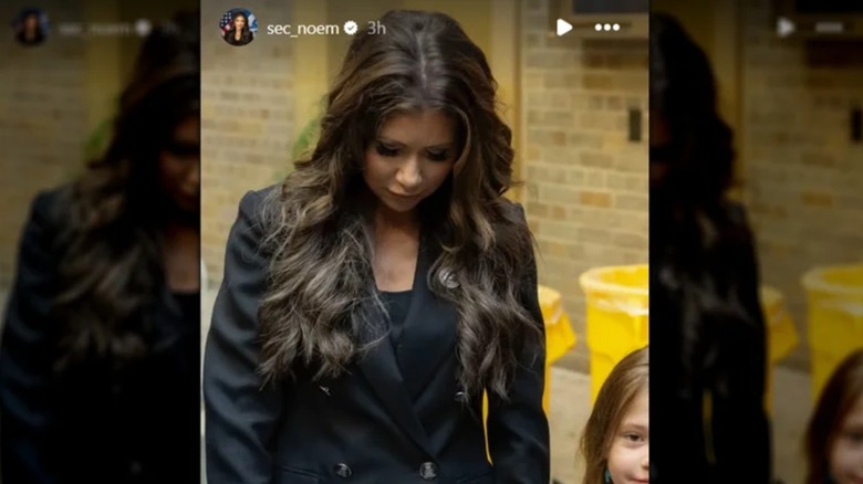 Kristi Noem regarde vers le bas et montre sa mauvaise application d'extensions de cheveux.