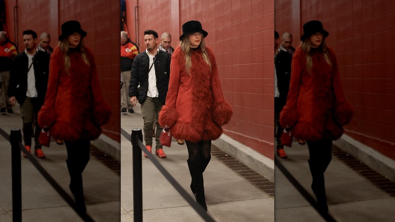 Taylor Swift marchant dans un manteau bordé de fourrure rouge et des bottes