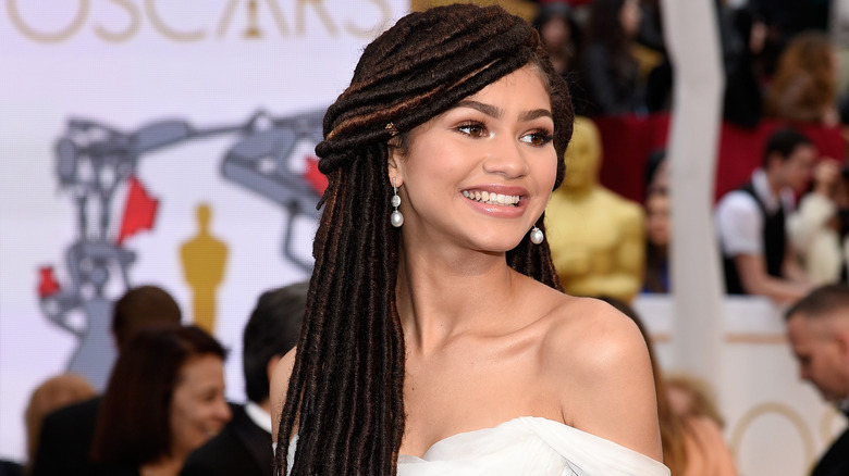 Zendaya sourit en marchant sur le tapis rouge des Oscars 2015