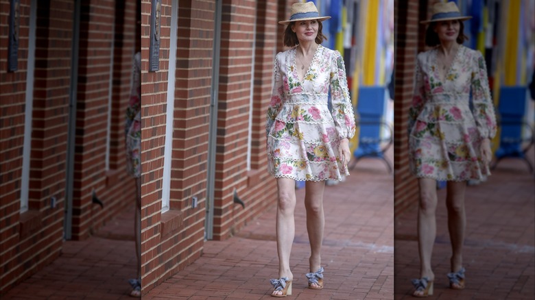 Geena Davis portant une robe blanche à fleurs et un chapeau de paille en marchant