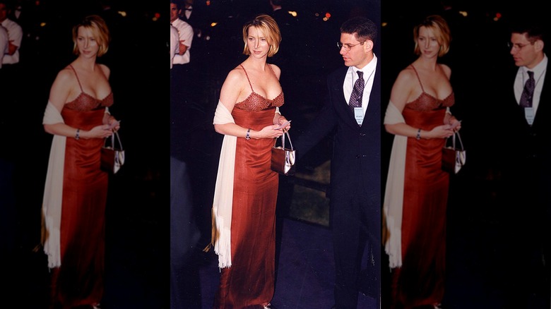 Lisa Kudrow posant lors d'un événement sur le tapis rouge dans une robe rouge avec un foulard blanc et des cheveux courts.