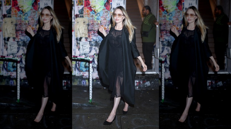 Angelina Jolie marche vêtue d'un blazer noir et d'une robe transparente