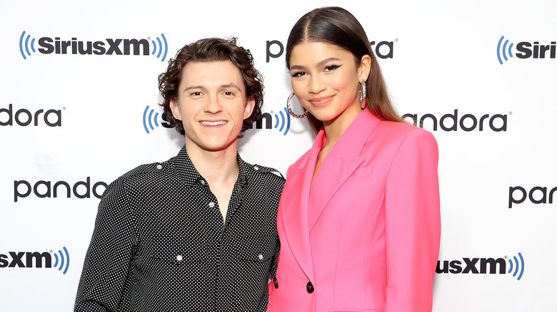Zendaya et Tom Holland posant ensemble, avec Zendaya dans un blazer rose
