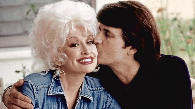 Dolly Parton dans une veste en jean recevant un baiser sur la joue de son défunt mari Carl Dean.