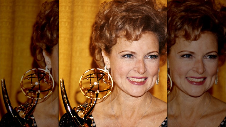 Betty White, actrice américaine, souriante alors qu'elle tient un Emmy Award, sur fond jaune, États-Unis, vers 1975