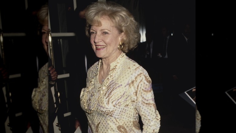 L'actrice et comédienne américaine Betty White, vêtue d'une robe à motif imprimé jaune, sourit alors qu'elle assiste à la 5e édition des Genesis Awards, décernée par la Humane Society of the United States (HSUS) pour sensibiliser le public aux questions relatives aux droits des animaux, qui s'est tenue à l'hôtel Beverly Wilshire à Beverly Hills, Californie, le 3 février 1991.