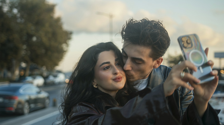 Une femme prend un selfie tandis qu'un homme l'embrasse