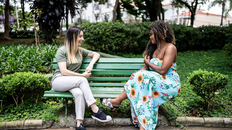 Deux femmes parlant sur un banc dans un parc