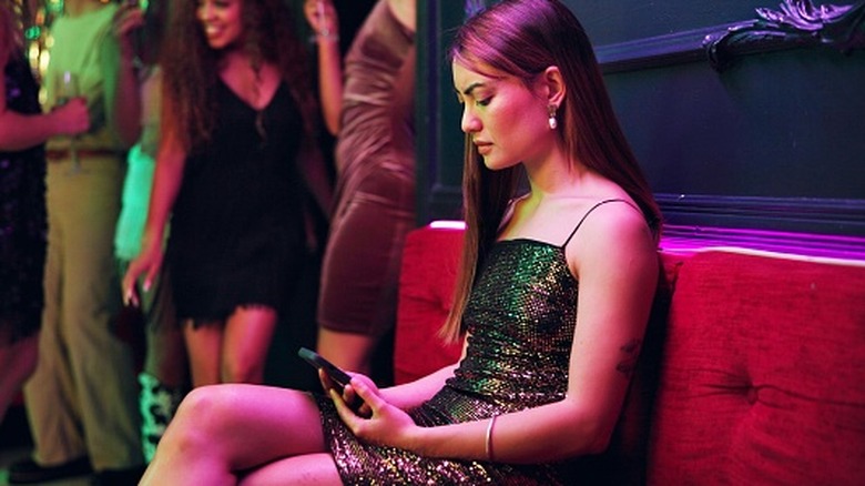 Une femme vérifie son téléphone dans un club après avoir été fantôme