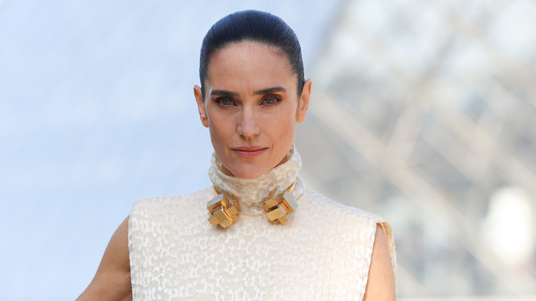 Jennifer Connelly pose dans une robe blanche avec un collier en or