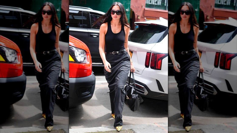 Dua Lipa porte un débardeur noir à encolure dégagée et un pantalon noir.