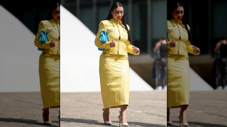 Une femme vêtue d'une robe jaune et d'une jupe crayon