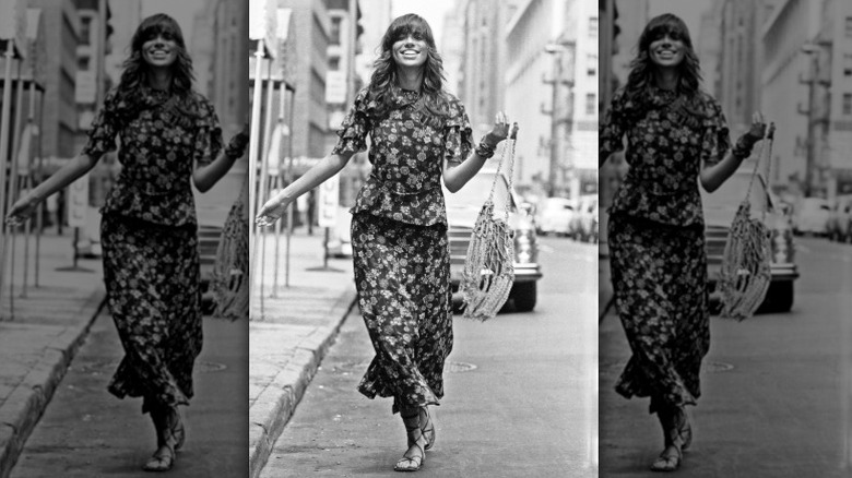 Carly Simon sourit dans la rue dans une tenue fleurie deux pièces