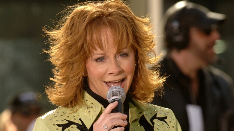 Reba McEntire chante et arbore une coupe de cheveux à franges superposées tout en portant une veste en cuir vert clair
