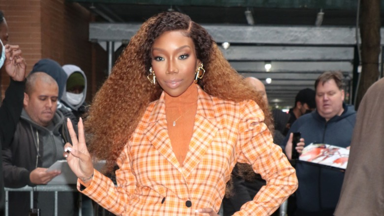 Brandy dans un blazer à carreaux et des cheveux bouclés volumineux