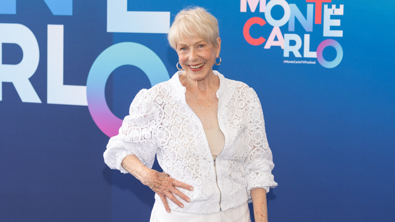 Karen Grassle pose avec sa main sur sa hanche, vêtue d'une tenue entièrement blanche et de boucles d'oreilles
