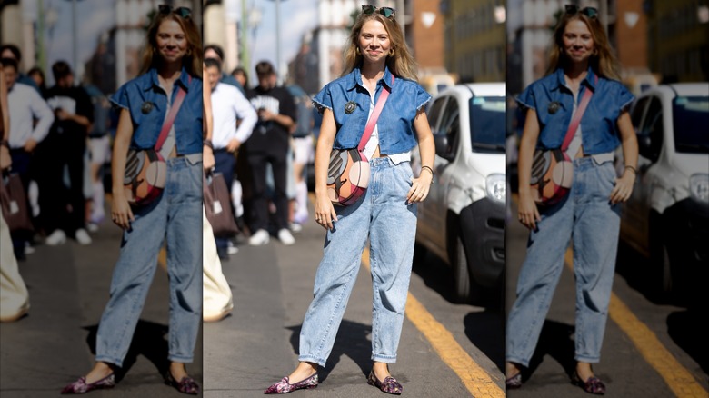 Une femme portant un jean mom légèrement délavé et une chemise en jean courte.