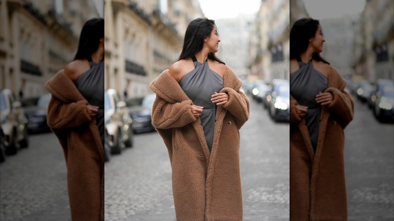 Une femme portant un long manteau ours en peluche à épaules dénudées.