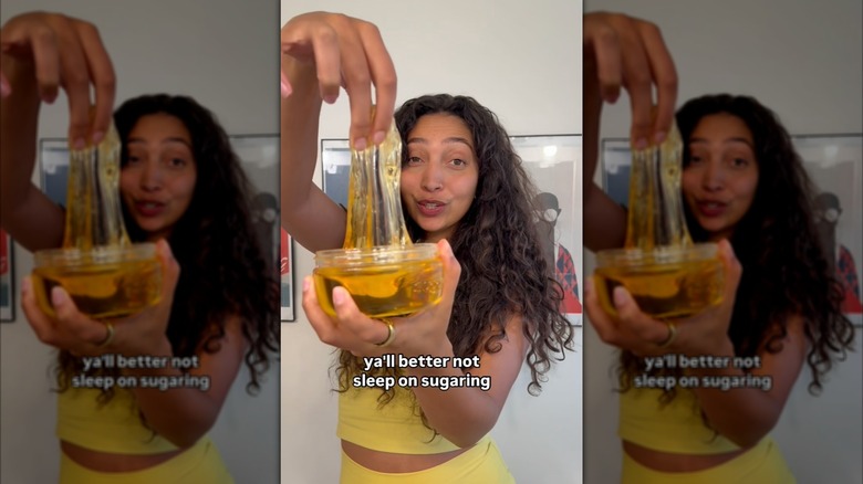 Vidéo Instagram d'Aliyah Marandiz portant une tenue jaune et tenant un pot de produit d'épilation Sugardoh.
