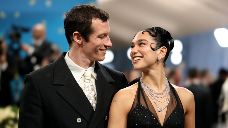 Callum Turner et Dua Lipa se sourient sur un tapis rouge