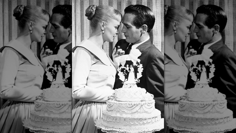 Joanne Woodward et Paul Newman debout derrière leur gâteau de mariage en 1958.