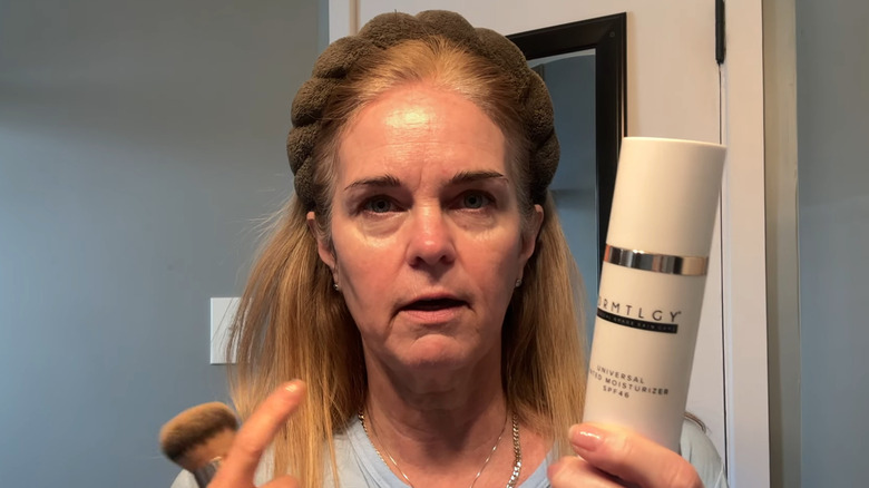 Femme tenant une crème hydratante teintée DRMTLGY