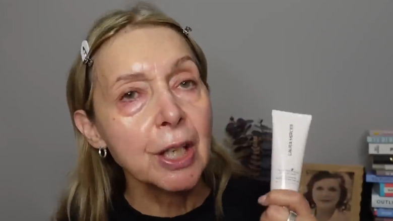 Femme tenant une crème hydratante teintée Laura Mercier