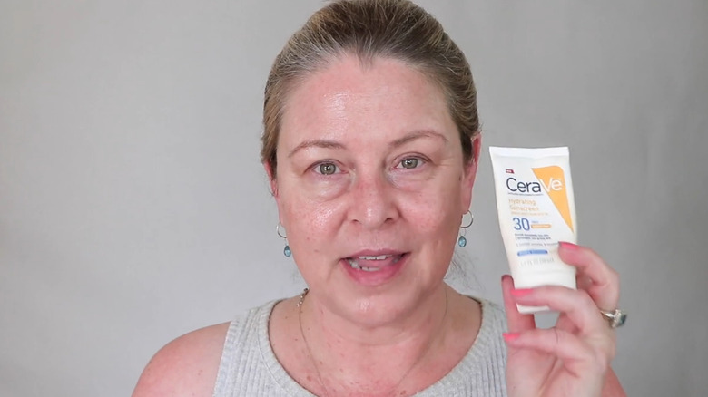 Femme tenant une crème solaire hydratante CeraVe