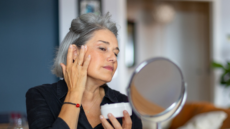 Femme mature appliquant un produit de soin