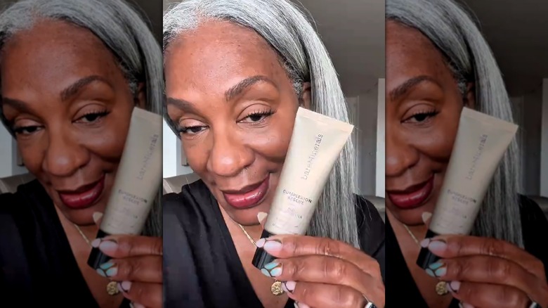 Femme tenant une crème hydratante teintée Bare Minerals Complexion Rescue