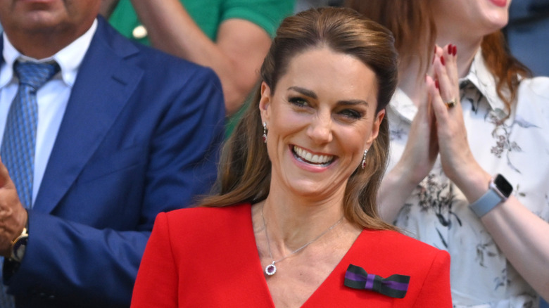 Kate Middleton souriante en portant une robe rouge