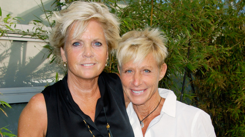 Meredith Baxter et sa femme Nancy Locke posent ensemble devant un feuillage vert en arrière-plan.