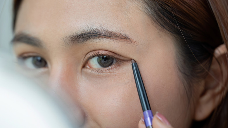 Gros plan d'une femme appliquant un eye-liner subtil