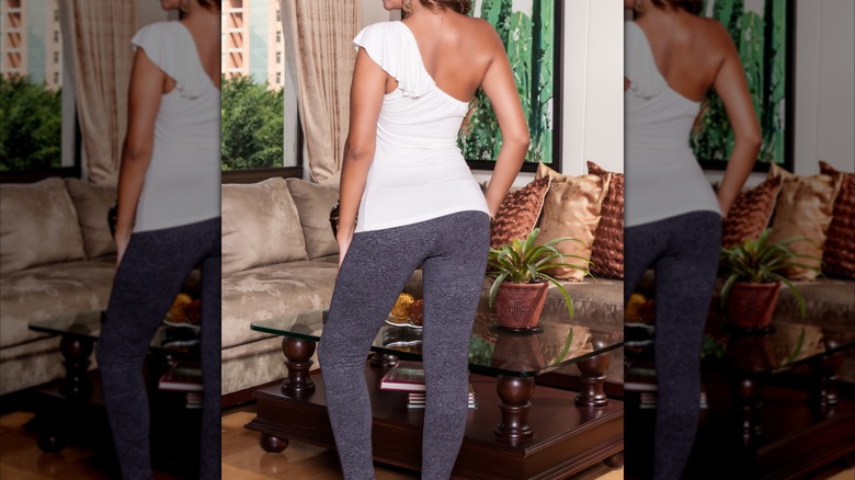 Femme portant un haut ajusté blanc et des leggings gris