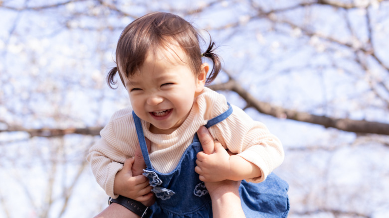 Famille tenant sa petite fille sous les fleurs de cerisier