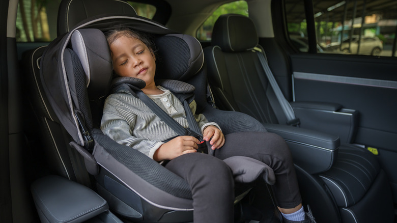 Fille d'enfant d'âge préscolaire assise et dormant dans le siège auto, chaise bébé de sécurité voyageant