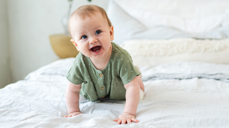 Bébé qui rit rampant sur un lit