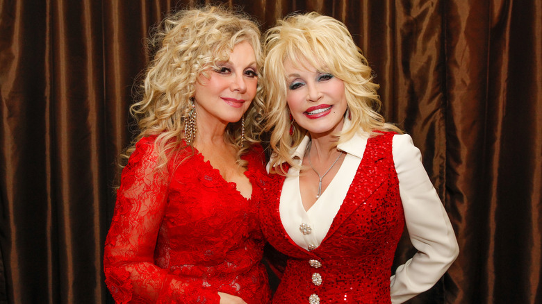 Stella Parton et Dolly Parton posent ensemble dans des tenues rouges scintillantes assorties.
