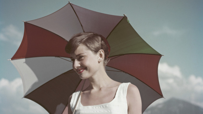 Audrey Hepburn souriante sous un parapluie coloré