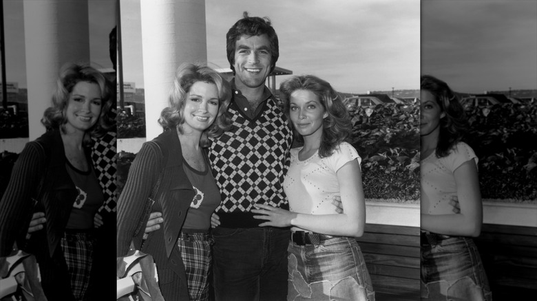 Deidre Hall (à gauche) sourit en portant un cardigan à côté de Tom Selleck (au milieu) et Jaime Lyn Bauer (à droite)