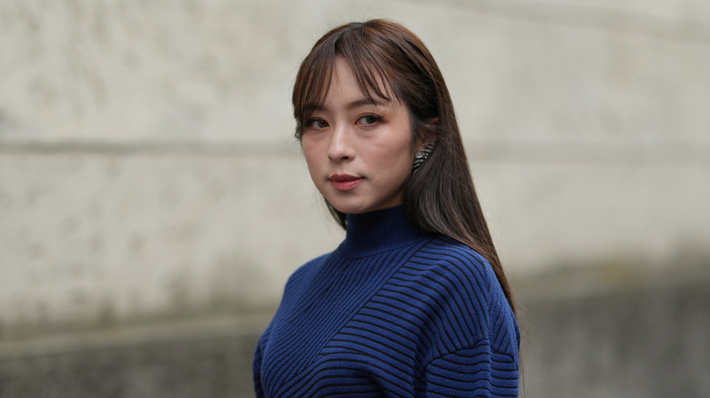 Une femme avec une frange de rideau brune et de longs cheveux raides