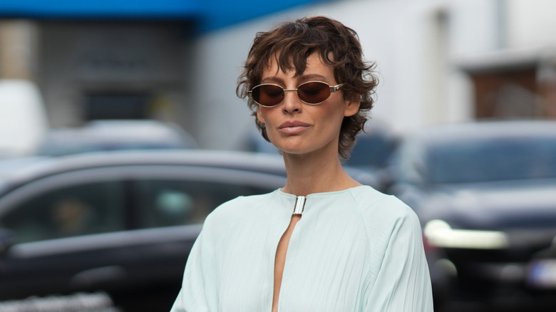 Une personne avec un bixie bouclé portant des lunettes de soleil