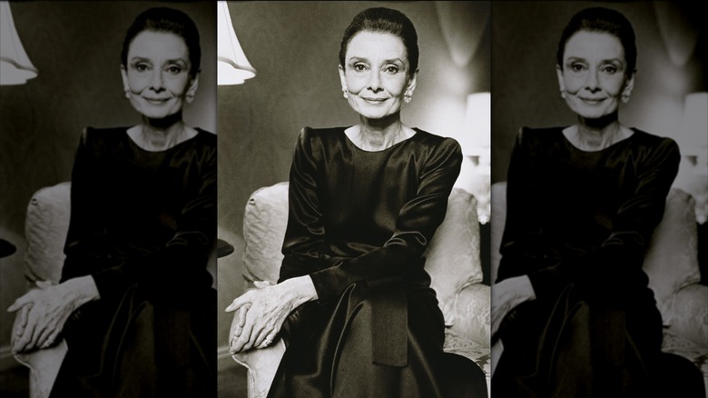 Audrey Hepburn posant pour un portrait vêtue d'une robe noire satinée à manches longues.