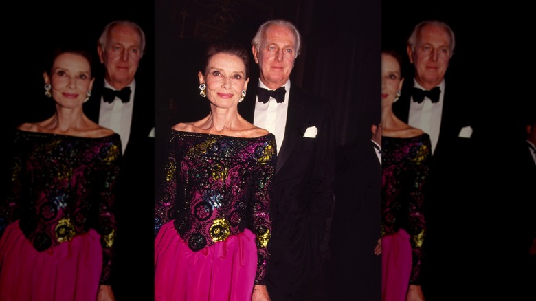 Audrey Hepburn dans une robe à épaules dénudées aux motifs élaborés et le créateur de mode français Hubert de Givenchy en smoking lors d'un événement de mode.