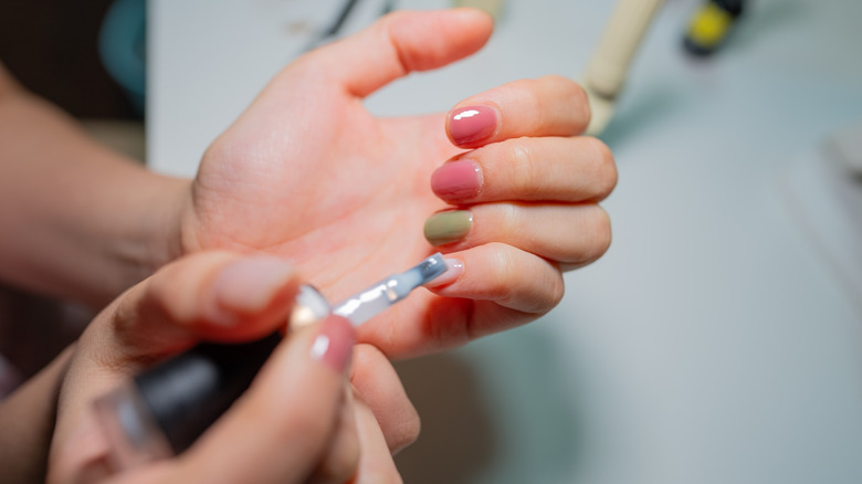 Une personne peignant différentes couleurs de vernis gel sur ses ongles