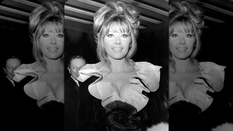 Ingrid Pitt sourit dans une robe noire avec un col blanc à volants