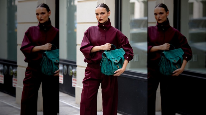 Femme dans une tenue bordeaux tenant un sac vert